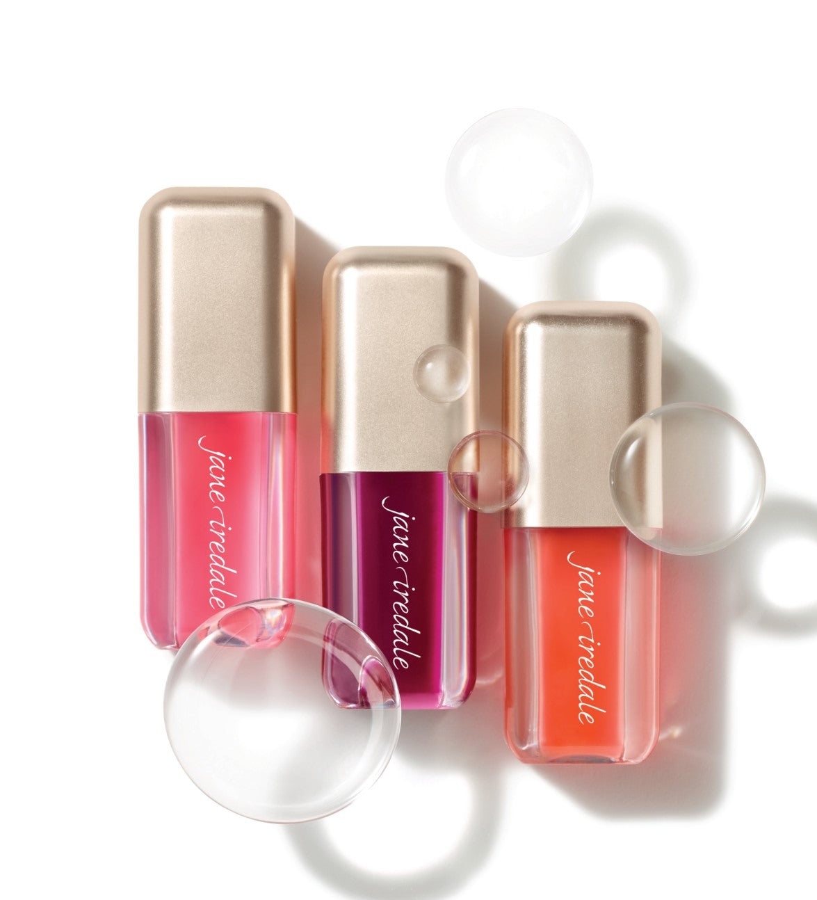 Three Jane Iredale pH Lip Oil minis in Blooming Pink, Blooming Berry and Blooming Peach with glossy bubble styling